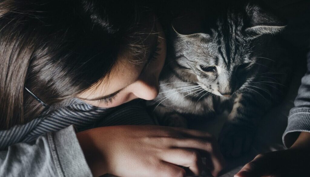 girl holding smartphone beside cat watching reclining to her shoulder