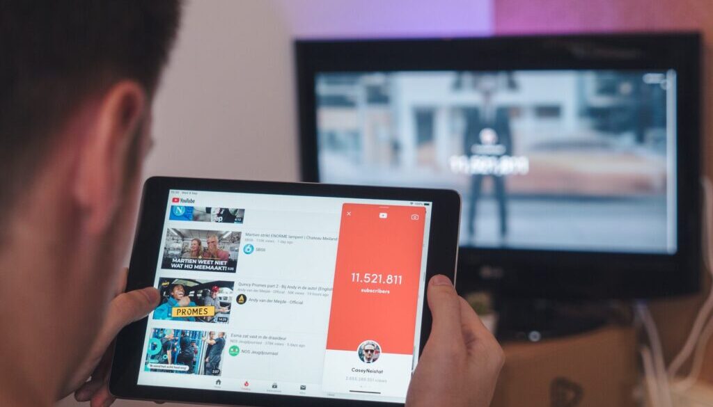 man browsing tablet sitting in front of TV
