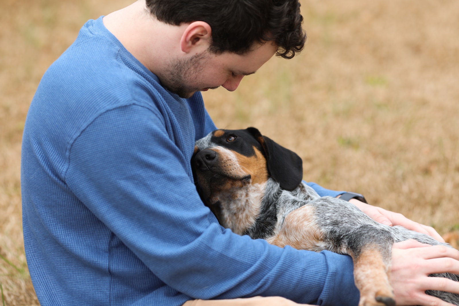 - NeposlušnéTlapky man in blue shirt hugging black and white short coated dog