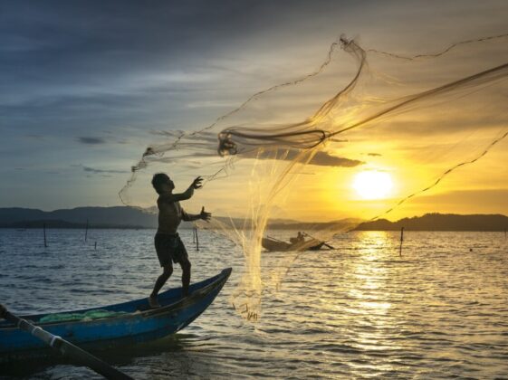 Fisherman throwing Fish Net on Lake