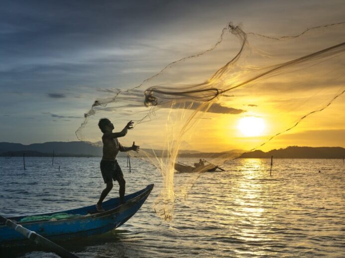 Fisherman throwing Fish Net on Lake