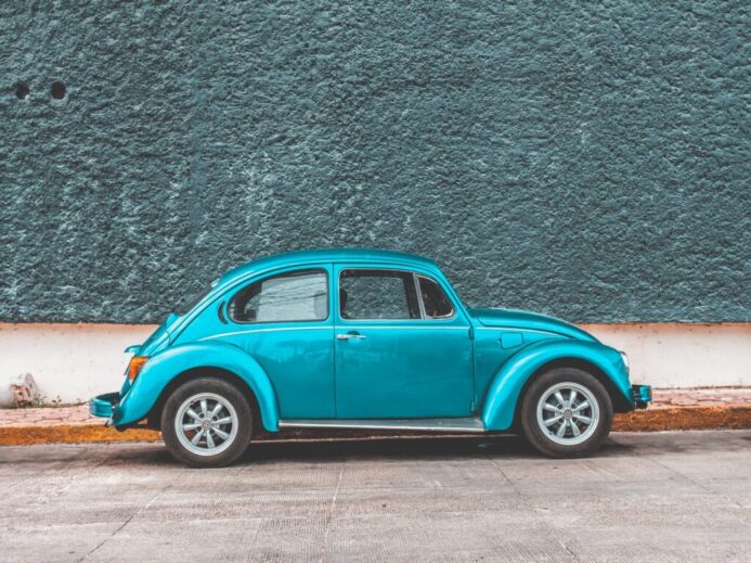 teal Volkswagen Beetle car parked beside sidewalk