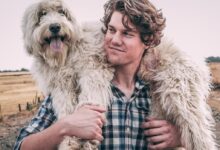 man carrying long-coated white dog