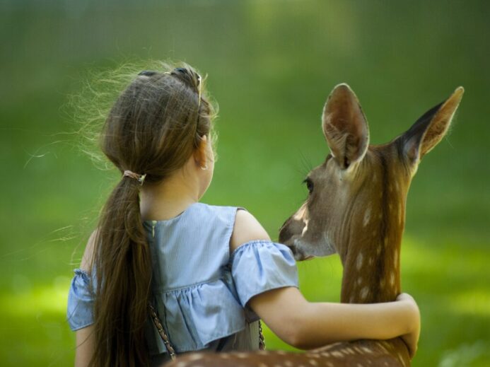 Girl Wearing Blue Top With her hand around a deer