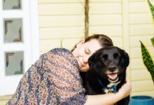 woman hugging black dog
