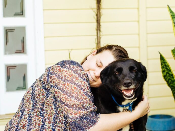 woman hugging black dog