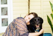 woman hugging black dog