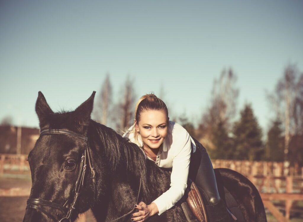 woman in white hoodie riding black horse