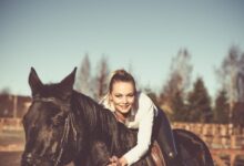 woman in white hoodie riding black horse