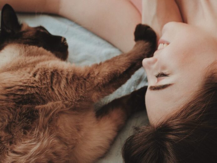 woman lying beside brown cat