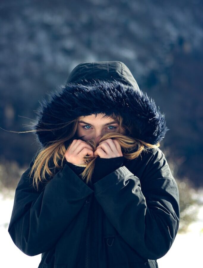 woman in black leather jacket covering her face with her hands