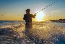 man in black jacket fishing on sea during daytime