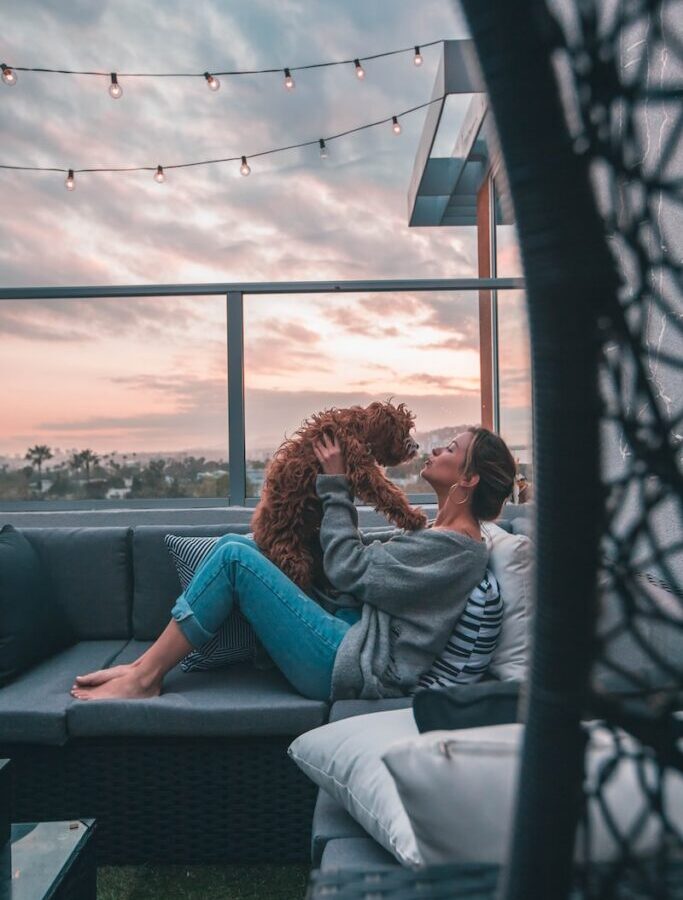 woman holding dog while sitting on sofa