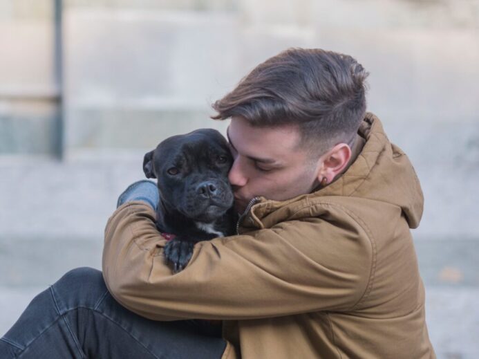 selective focus photography of man hugging black dog