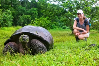 Želva obrovská s mladou ženou na ostrově Santa Cruz v Galapážském národním parku v Ekvádoru