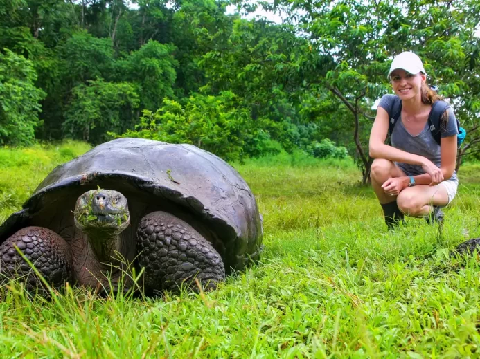 Želva obrovská s mladou ženou na ostrově Santa Cruz v Galapážském národním parku v Ekvádoru