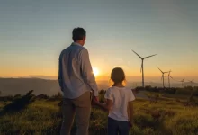 Muž s chlapcem se dívají na větrné elektrárny v západu slunce