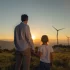Muž s chlapcem se dívají na větrné elektrárny v západu slunce