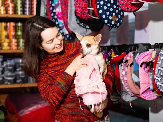 Žena vybírá v obchodě obleček pro psíka